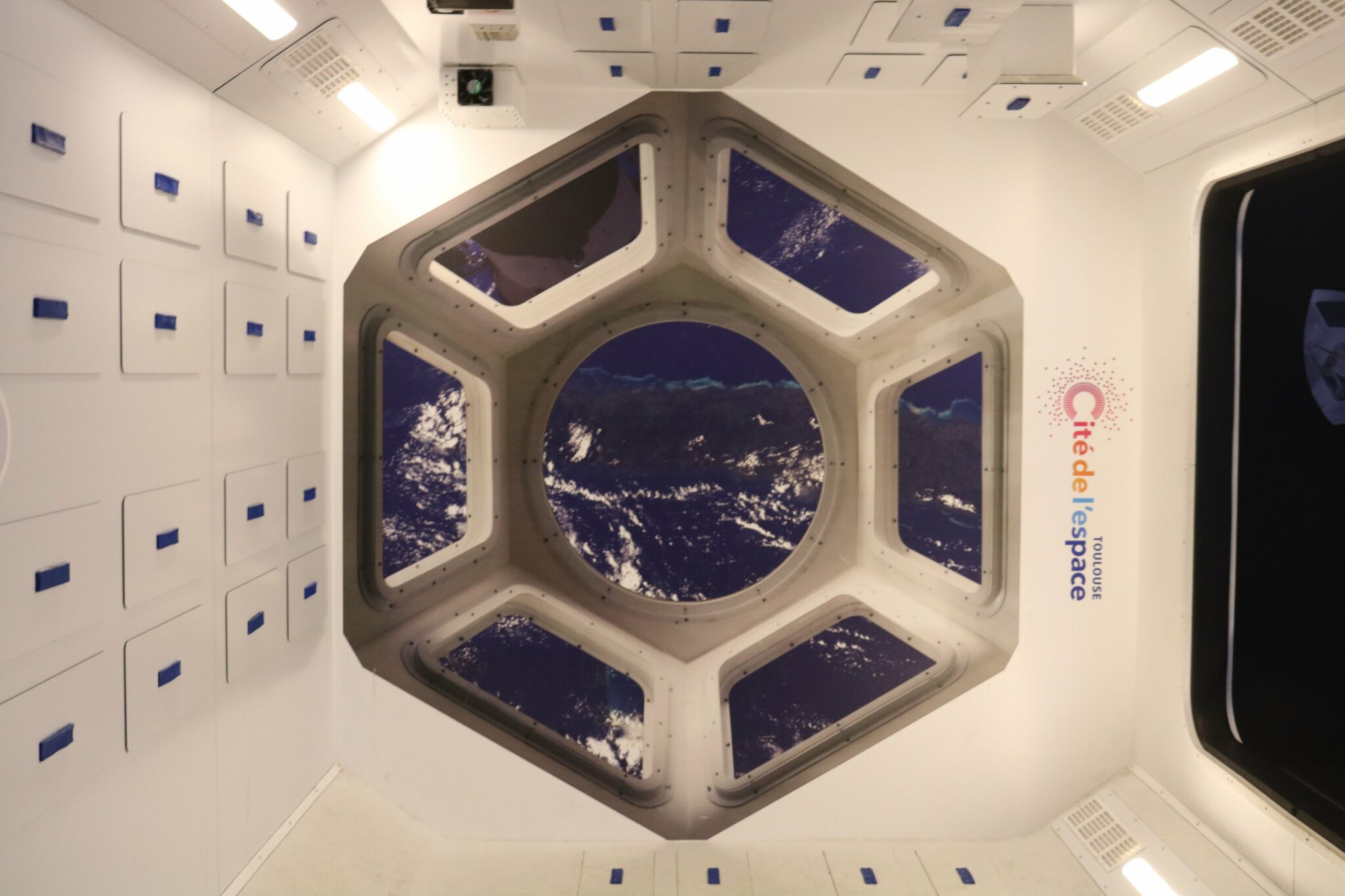La station spatiale internationale (ISS), dont la vue depuis un de ses hublots est reproduite ici, accueille en permanence par un équipage international qui se consacre à la recherche scientifique dans l'environnement spatial. Ce laboratoire en apesanteur permet ainsi de mener des recherches essentielles à l’implantation de la vie humaine sur une autre planète.